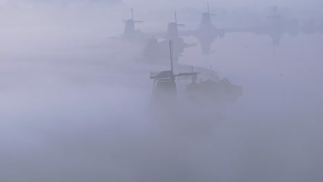 Fila-De-Molinos-De-Viento-Tradicionales-En-Los-Países-Bajos-Durante-El-Amanecer-Brumoso,-Aéreo