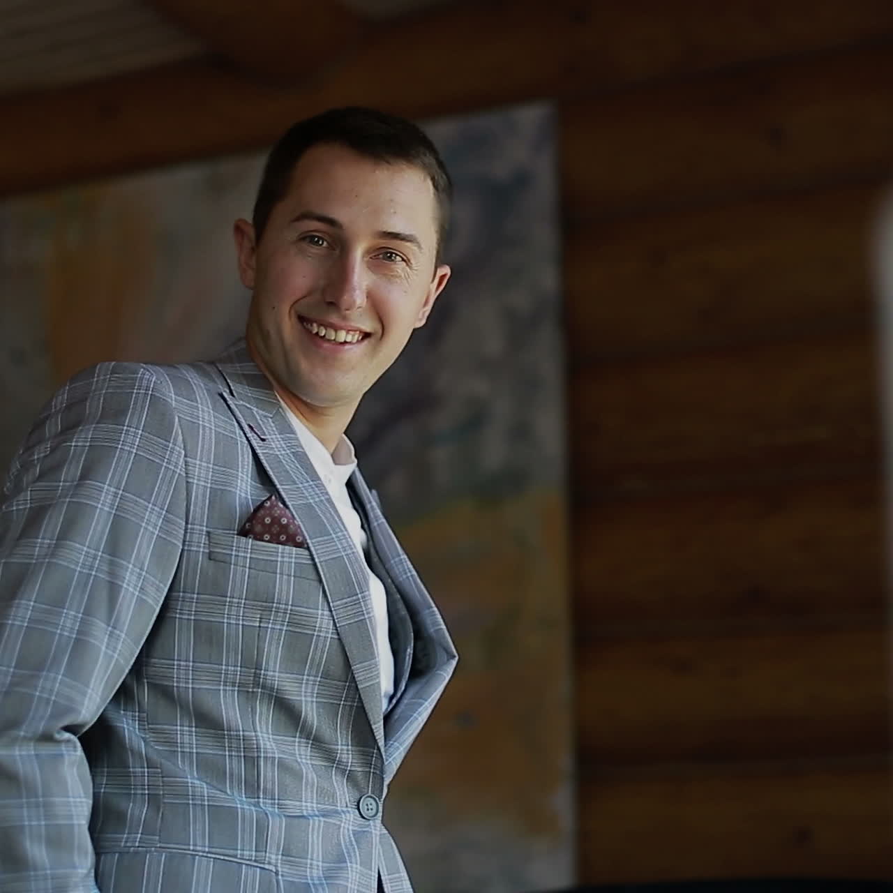 Young handsome man is wearing a jacket, standing in front of a window. Men's Clothing. Square video