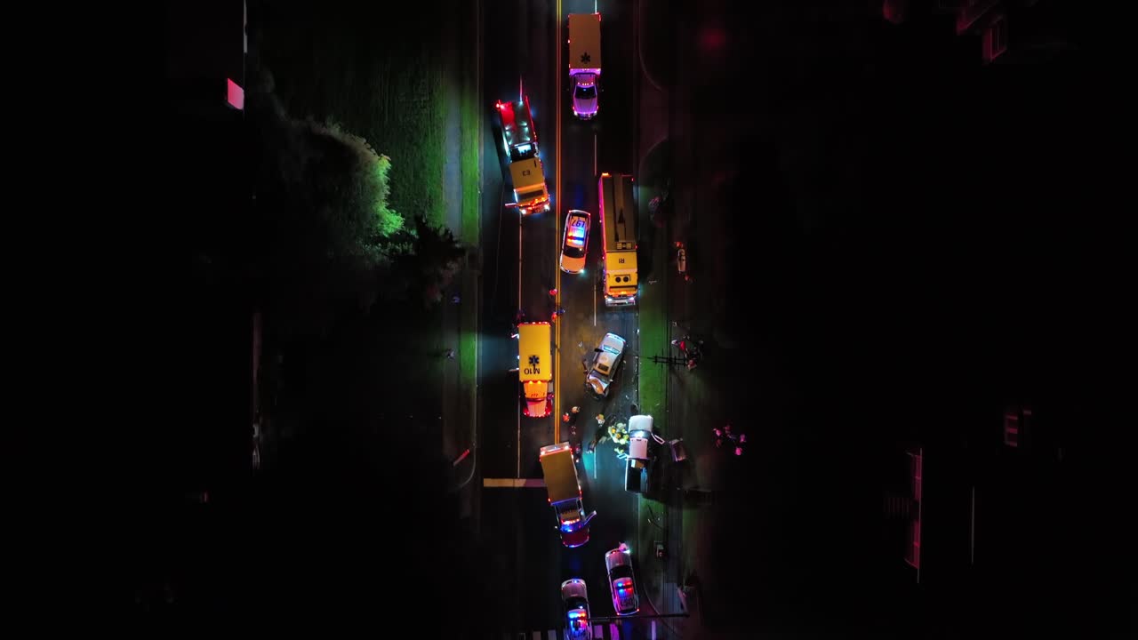 Flashing emergency lights of police cars and ambulance at night. Frontal Car accident on American highway at night. Aerial top down flyover.