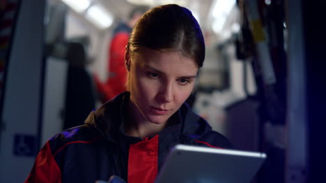 Focused-female-paramedic-using-digital-tablet-at-work