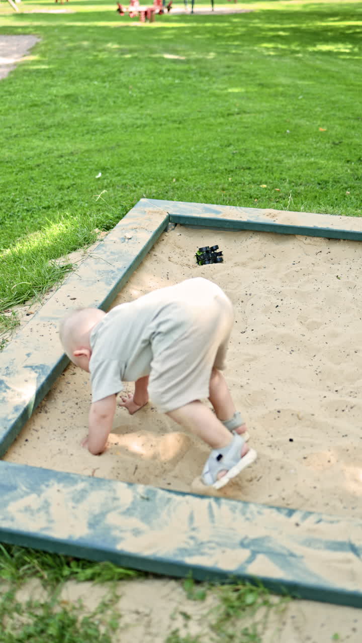 Un bambino carino che gioca nella sabbiera al parco giochi. Bambino che scava la sabbia nella sabbiera all'aperto. Sviluppo e apprendimento del bambino giocando con la sabbia. Bambino in pantaloncini e maglietta nella sabbiera.
