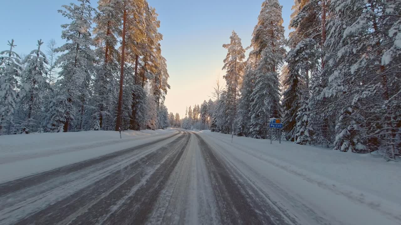 Winter sun reflects on ice covered rural forest roads commute travel POV