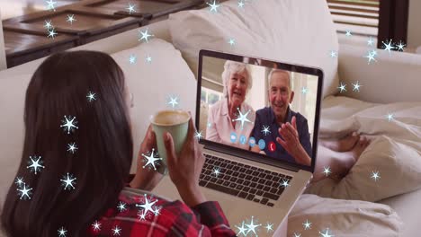 Animation-of-snow-falling-over-happy-caucasian-woman-on-laptop-video-call-with-her-family