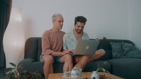 two men using a laptop on a couch