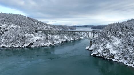 wide establishing aerial view of deception pass bridge during winter time