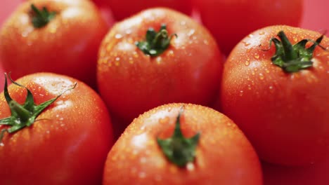 Video-of-close-up-of-fresh-red-tomatoes-on-pink-background