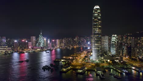 captured at night, the mesmerizing skyline of hong kong shines with colorful city lights. the bustling waterfront features boats and reflects the energy of this iconic metropolis.