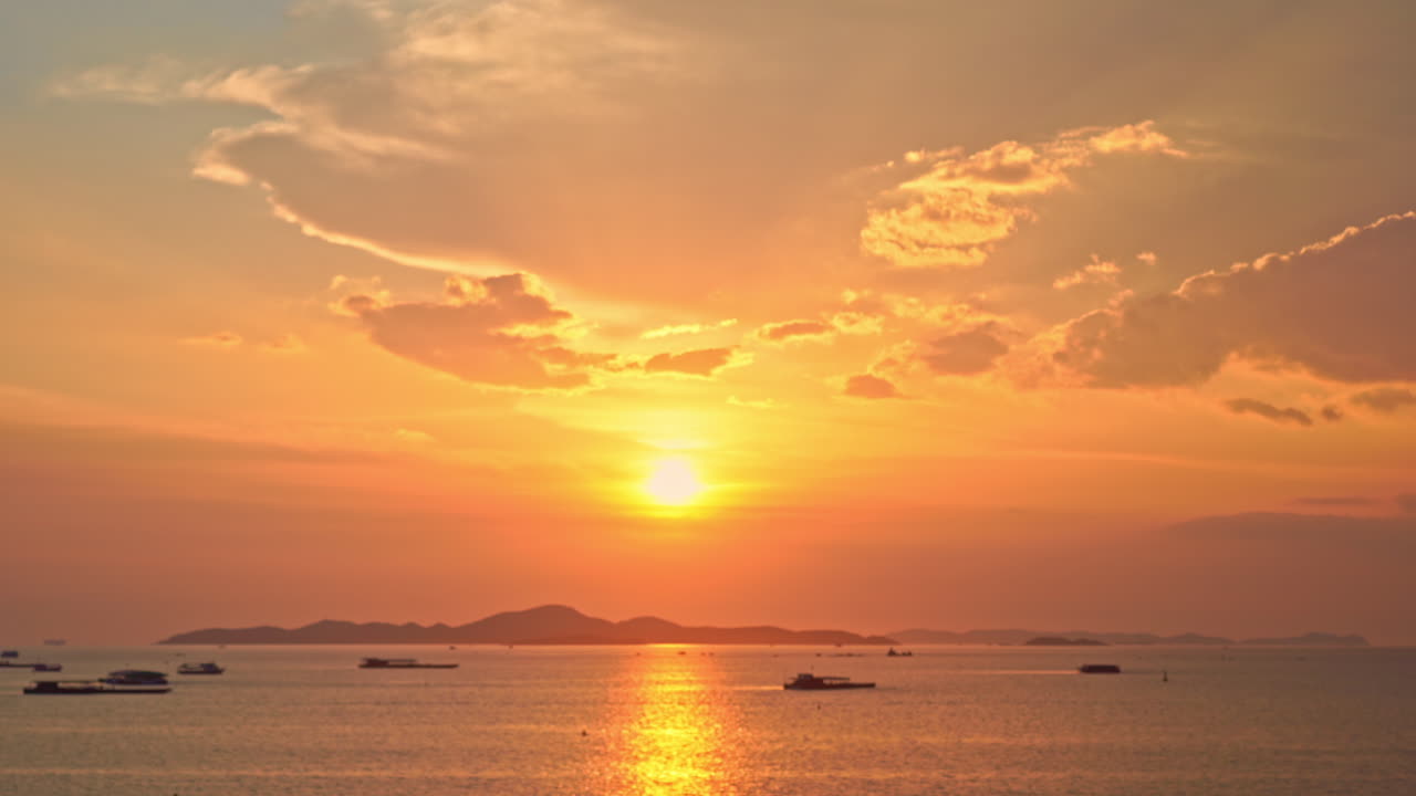 Seascape with dramatic orange sunset with partially cloudy sky