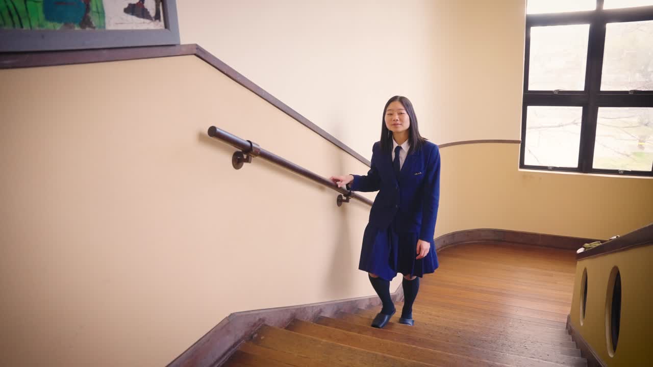 Japansk pige i skoleuniform går langsomt op ad trappen 4K.