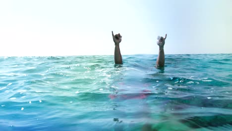 hombre buceando bajo el agua y haciendo rock and roll con el gesto de la mano