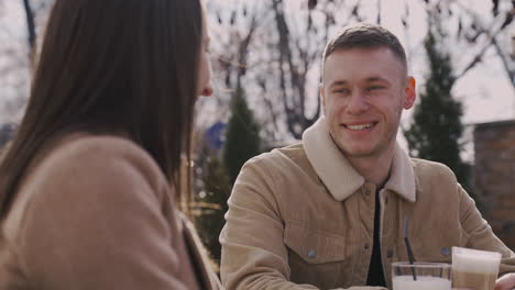 Girl-And-Boy-Laughing-Together-While-Sitting-At-Table-In-A-Bar-Terrace