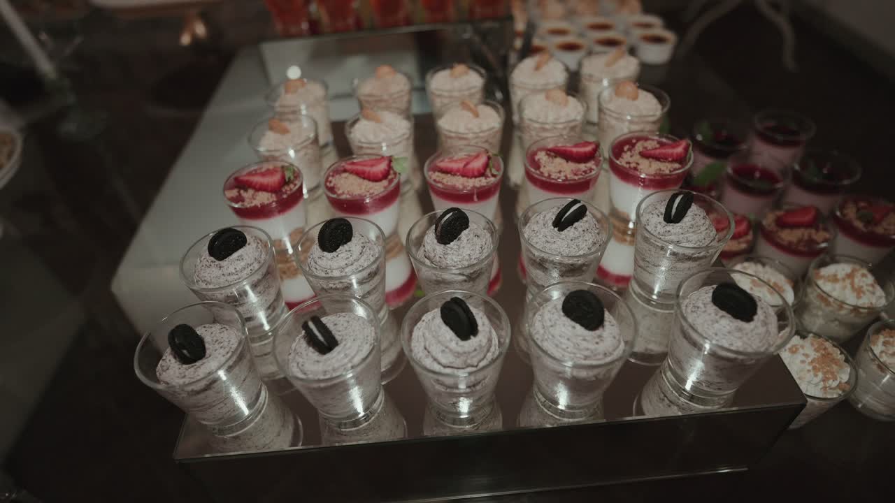 Elegant wedding display of assorted mini desserts in glass cups topped with fruits and cookies