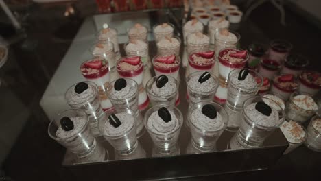 elegant wedding display of assorted mini desserts in glass cups topped with fruits and cookies