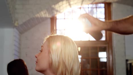 male hairdresser spraying hair spray on womans hair