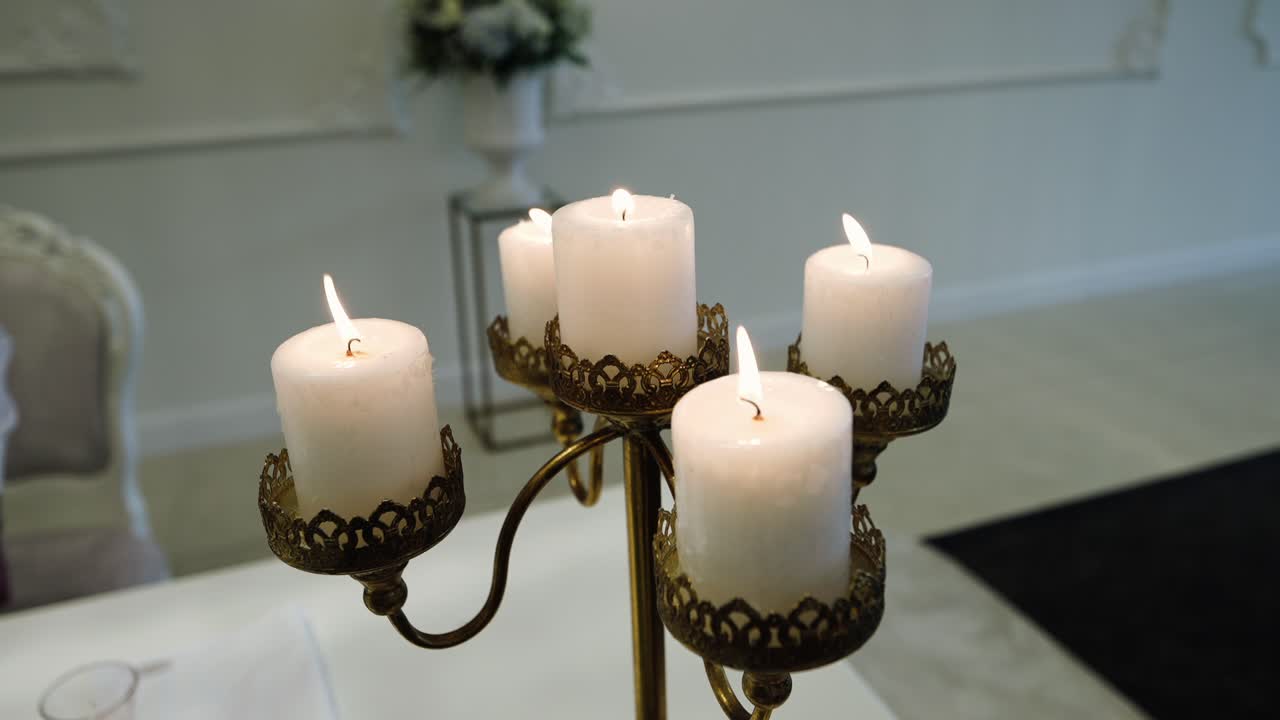 five glowing white candles burning in decorative golden holder