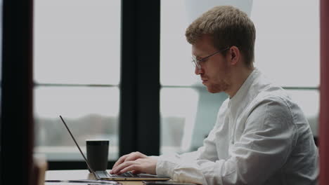 hombre caucásico adulto está trabajando en la oficina escribiendo mensajes en el teclado de la computadora portátil hablando en el trabajo hablando con sus socios