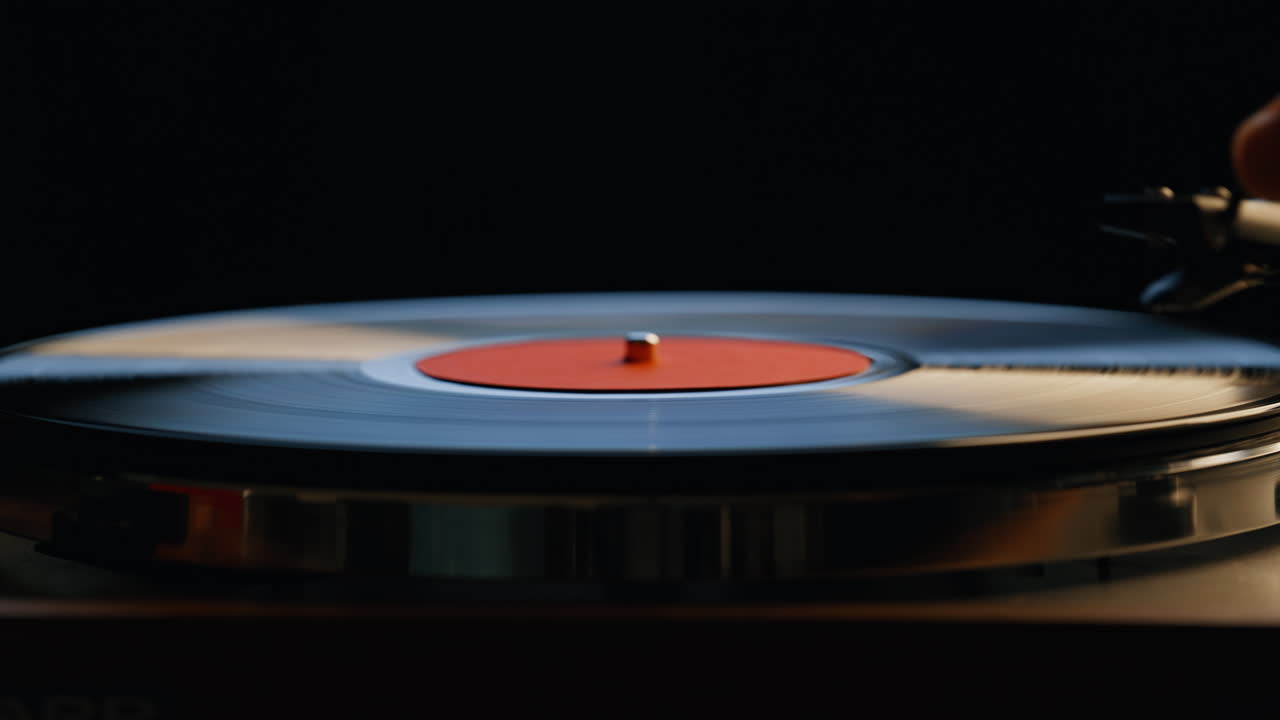 Hand turning off vinyl turntable in night room closeup. Unrecognizable man
