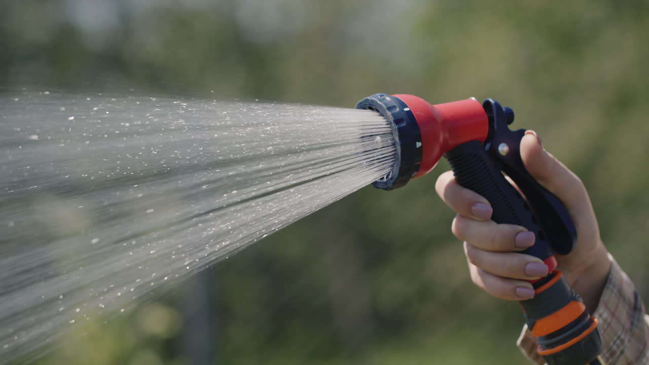 Gardener's hand sprays a garden hose with a diffuser 1