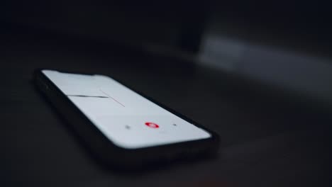 close up on smartphone with voice recording app listening and capturing conversation or criminal evidence. eavesdropping secretly under couch or bed in dark room at night. investigation surveillance