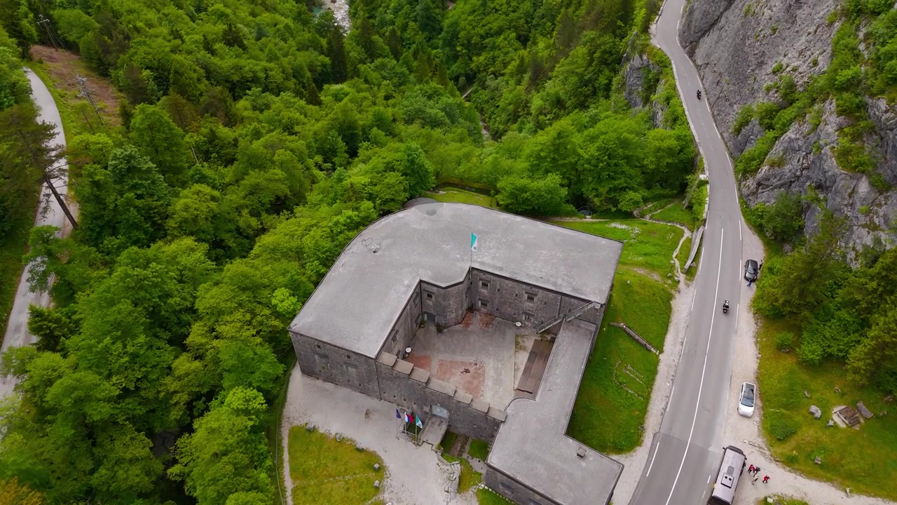Forte Kluže perto de Bovec, Eslovênia, exibindo a histórica fortaleza de montanha cercada por floresta, falésias e os Alpes Julianos, Dolly aéreo para frente