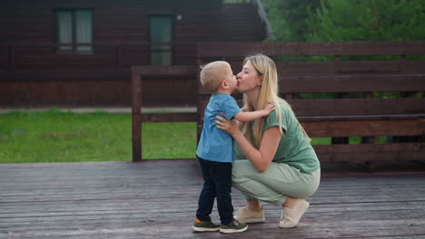 Mother-kisses-little-son-on-dance-ground-near-building