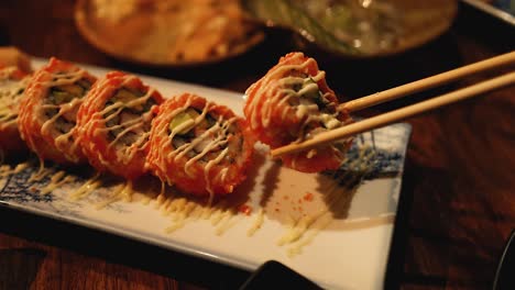 chopsticks picking sushi from a decorative plate