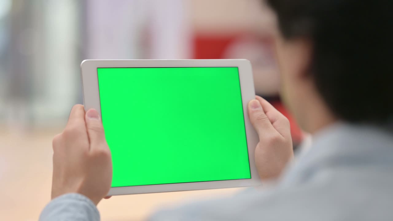 녹색 크로마 키 스크린으로 태블릿을 보는 남자