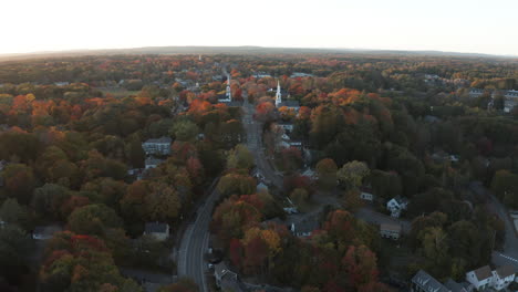 toma de drones de un pequeño pueblo entre coloridos árboles de otoño al atardecer