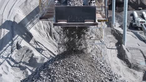 slow motion footage of gravel falling off a conveyor belt into a big pile in a quarry.