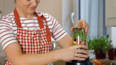 woman putting fruits in the mixer