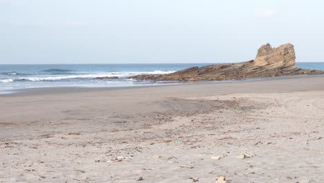 popoyo beach nicaragua with rocky ocean formations hit by waves, handheld wide shot