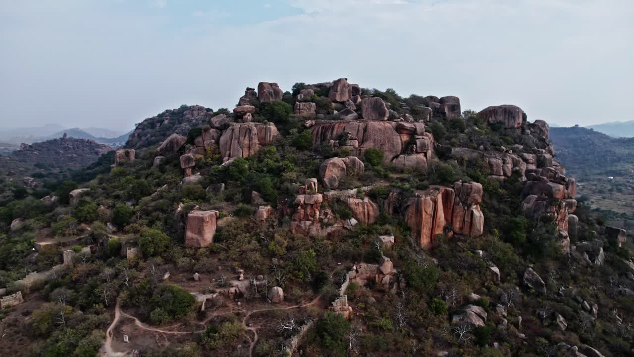 rock mountain hill with trees and clouds at rachakonda fort, telangana, india. day time, tilt down, drone shot, 4k.