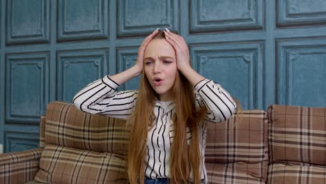 young woman sitting on a sofa and looking upset