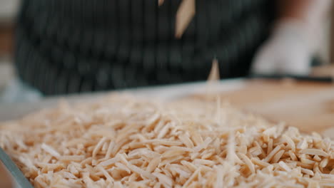 bakery worker picking up and releasing a handful of slivered almonds