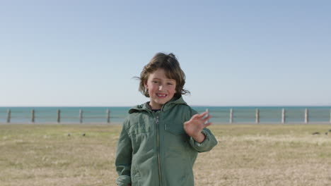 portrait of cute friendly boy at beach smiling waving happy at camera enjoying sunny day