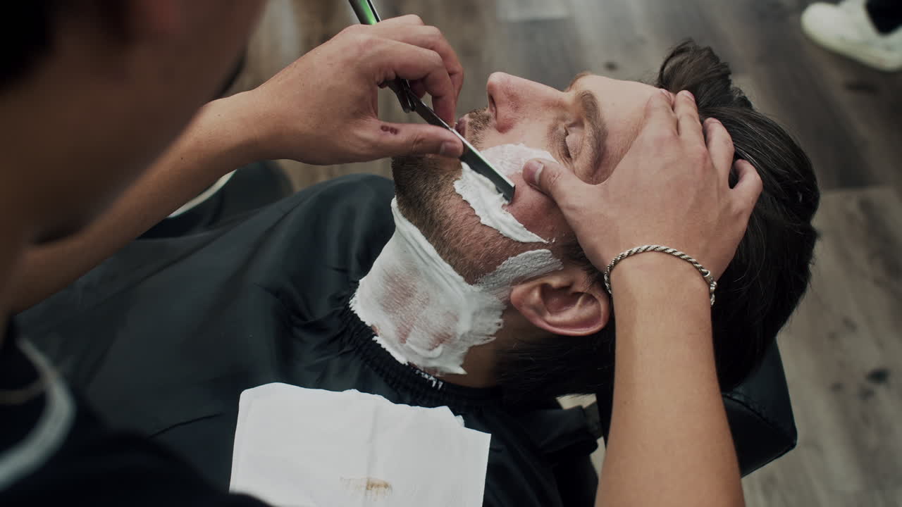 Mand, der bliver barberet i en barbershop
