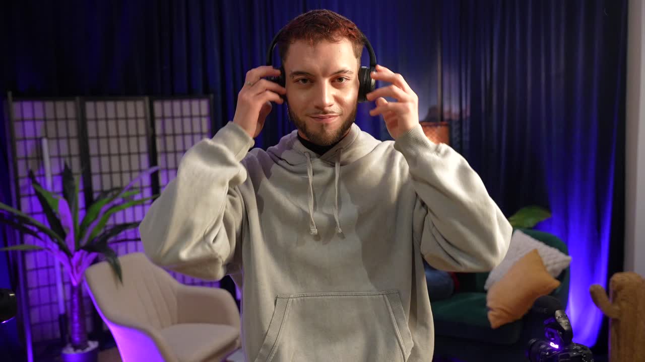 Giovane uomo indossa le cuffie e sorride in uno studio moderno.