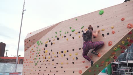 mujer subiendo a la pared de escalada al aire libre