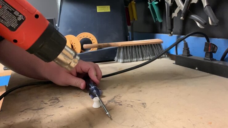 Man using hotgun to soften 3d printed parts, showing hands only, tripod static