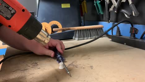 man using hotgun to soften 3d printed parts, showing hands only, tripod static