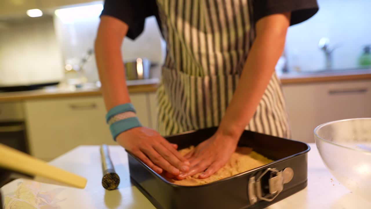 Hender som presser bunn i en bakeform på kjøkkenet