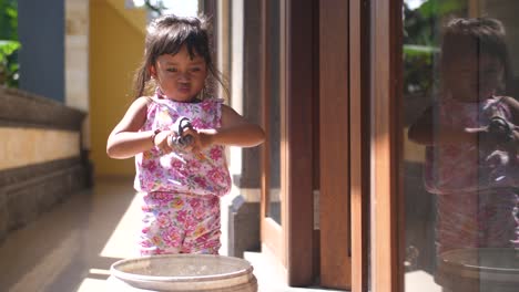 niñita haciendo tareas lavando puertas y ventanas sonríe y da pulgares hacia arriba mientras resopla