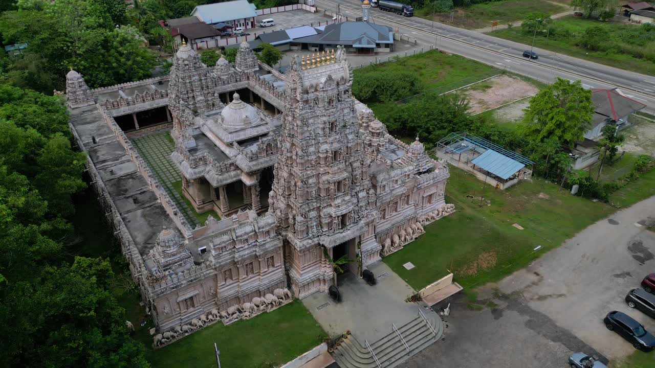 Ngoại thất đền thờ Hindu trang trí công phu với gopuram cao chót vót, những chạm khắc và tượng tinh xảo, được bao quanh bởi phong cảnh xanh tươi. Cảnh quay panorama tĩnh hoàn hảo từ drone trên không lơ lửng.