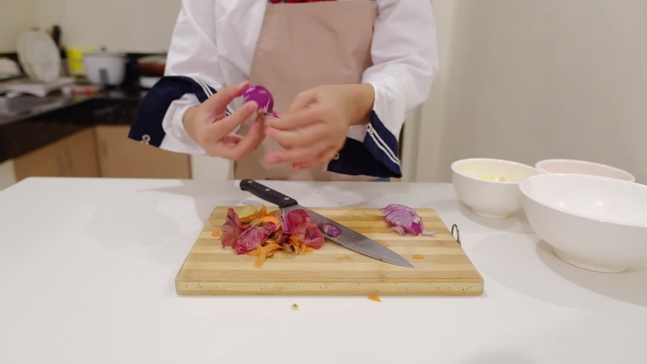 chef femenina pelando cebolla roja con las manos en la cocina