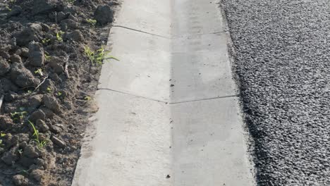 asphalt road with stormwater on the side of the road with a ditch for water and a glade of green lawn along the road.