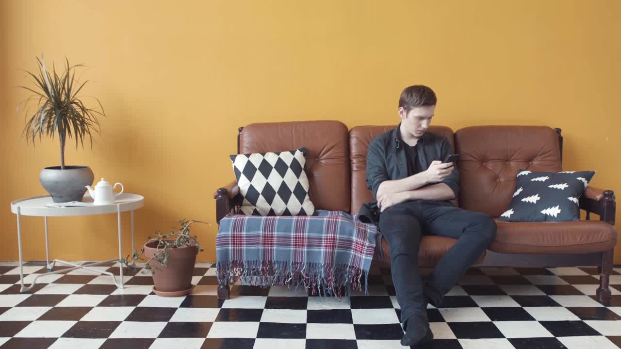 소파에서 스마트폰을 사용하는 남자
