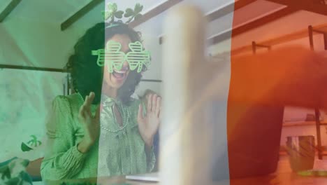 animation of flag of ireland and biracial woman in shamrock glasses celebrating st patrick's day