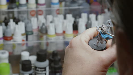 artist spinning and painting 3d printed miniature fantasy model in his studio with various color paint pots visible in background 4k