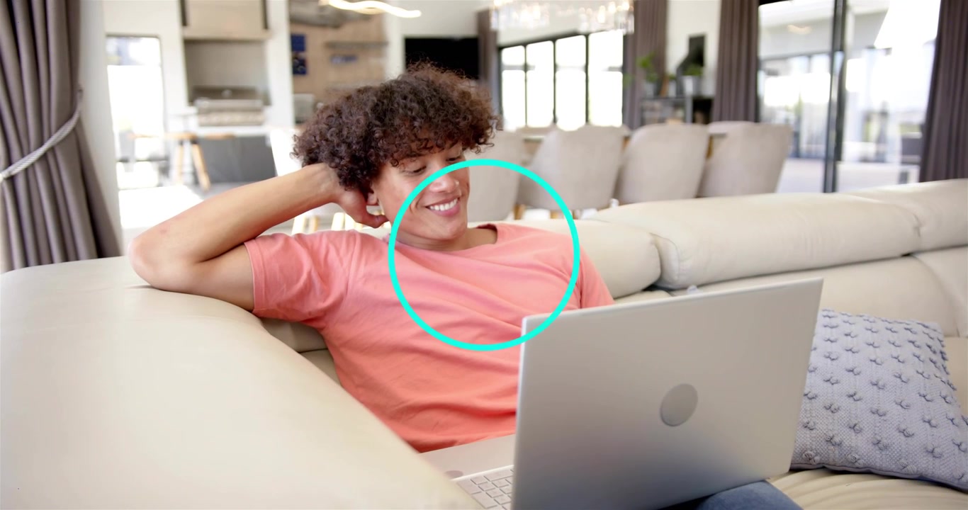 Uomo sdraiato sul divano che digita sul laptop, visualizzando punti blu animati sovrapposti al laptop, potenziando la tecnologia