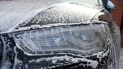 car headlight soaking in shampoo and bubbles after cleaning